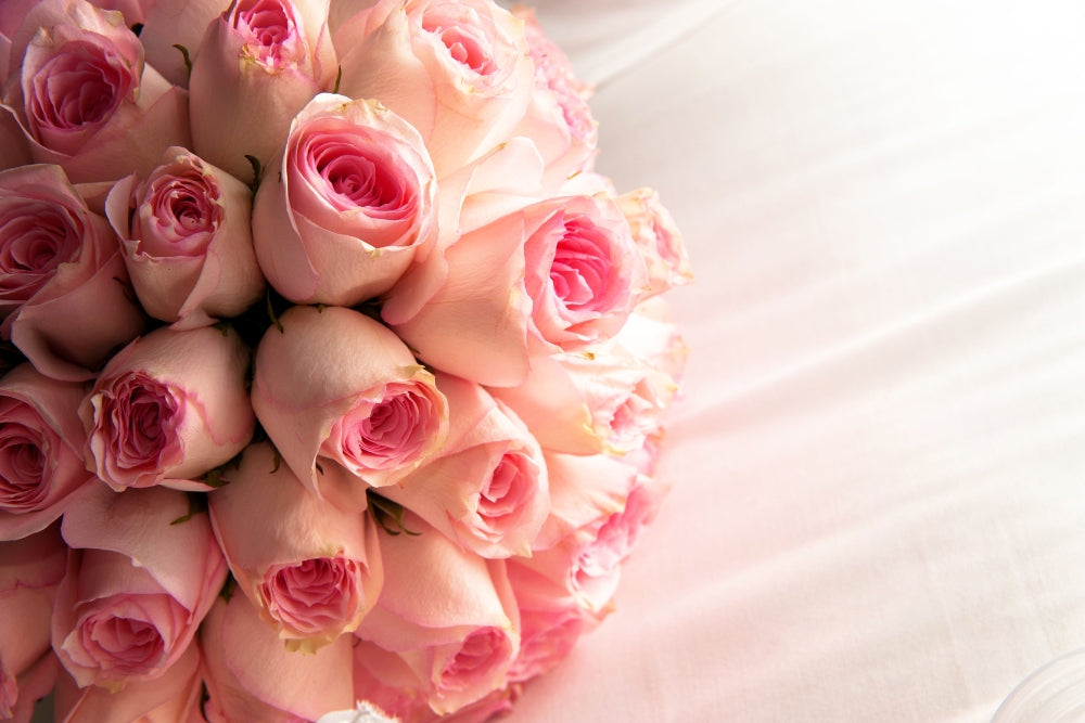 A pink bouquet of roses sits on a bed showing how long do roses last.