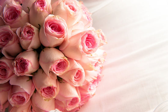 A pink bouquet of roses sits on a bed showing how long do roses last.