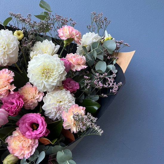 Bouquet of flowers with pink, white, and green colors against a blue background
