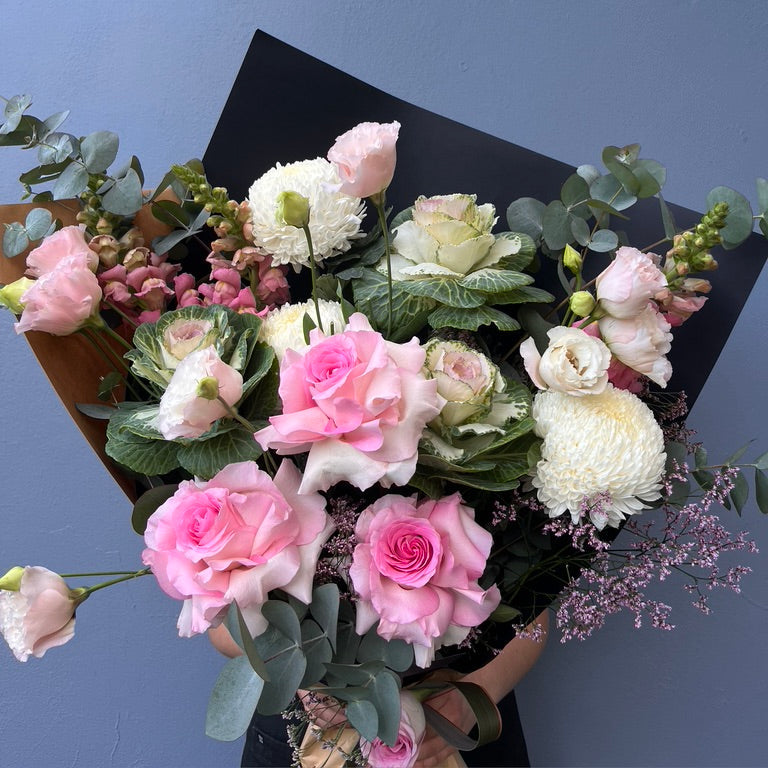 Bouquet of pink and white flowers with greenery against a blue background