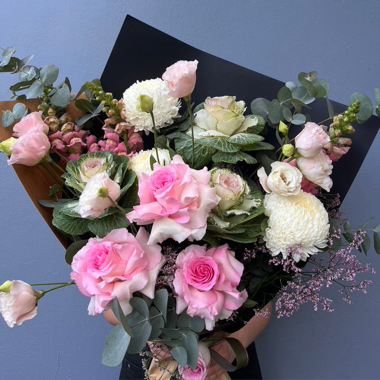 Bouquet of pink and white flowers with greenery against a blue background